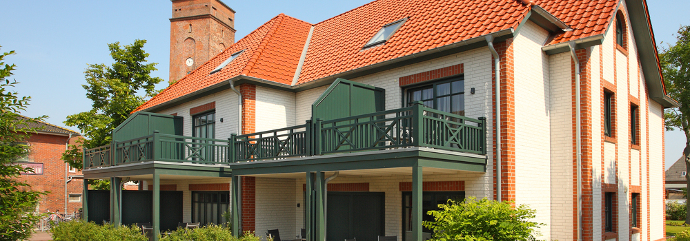 Villa am Marienhof mit rotem Ziegeldach und grünen Balkonen